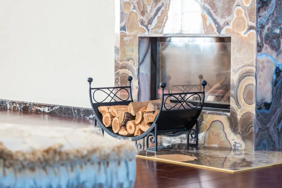 Interior of modern lounge decorated with marble fireplace with patterns and black wood rack