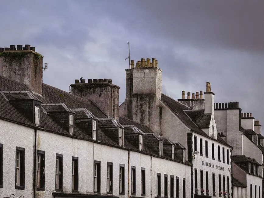 Old row houses with chimneys under cloudy skies, showcasing classic architecture.