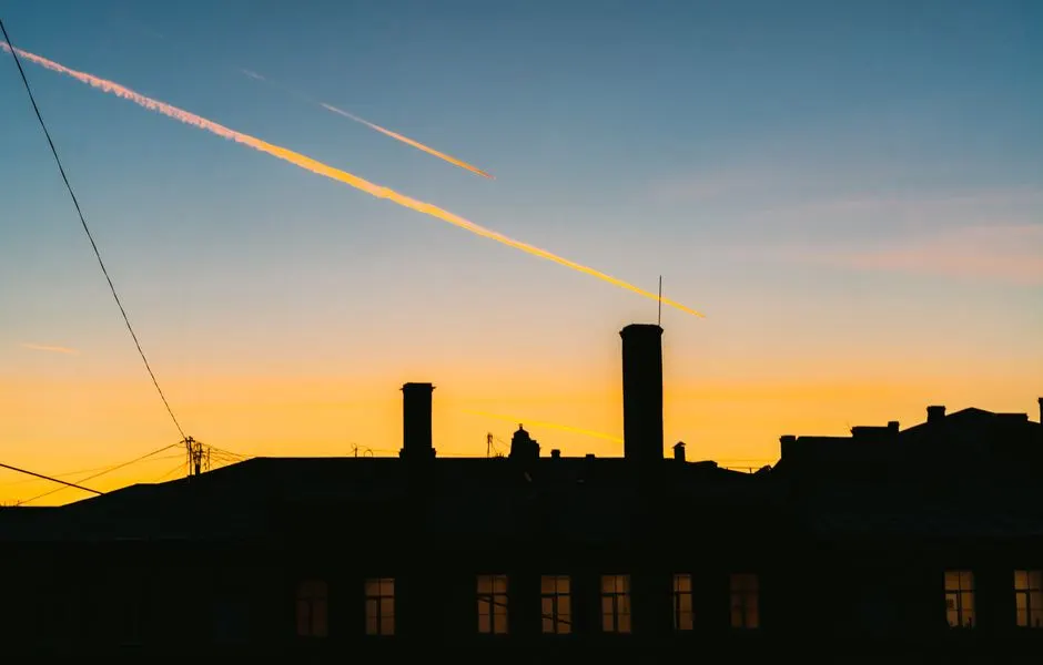 Silhouette of dwelling house exterior with chimneys and windows under colorful sky in town at sunset